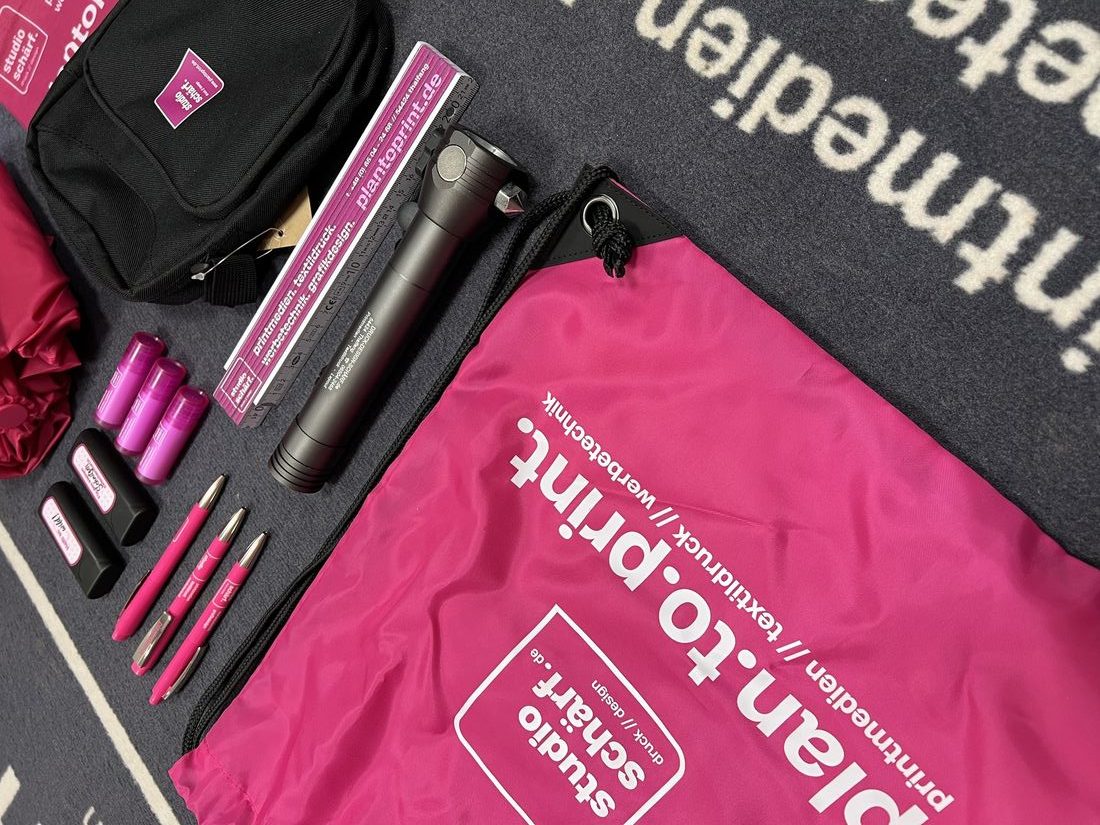 Werbeartikel in Pink und Schwarz: Turnbeutel, Taschenlampe, Stifte und Tasche mit studio-schärf.-Logo