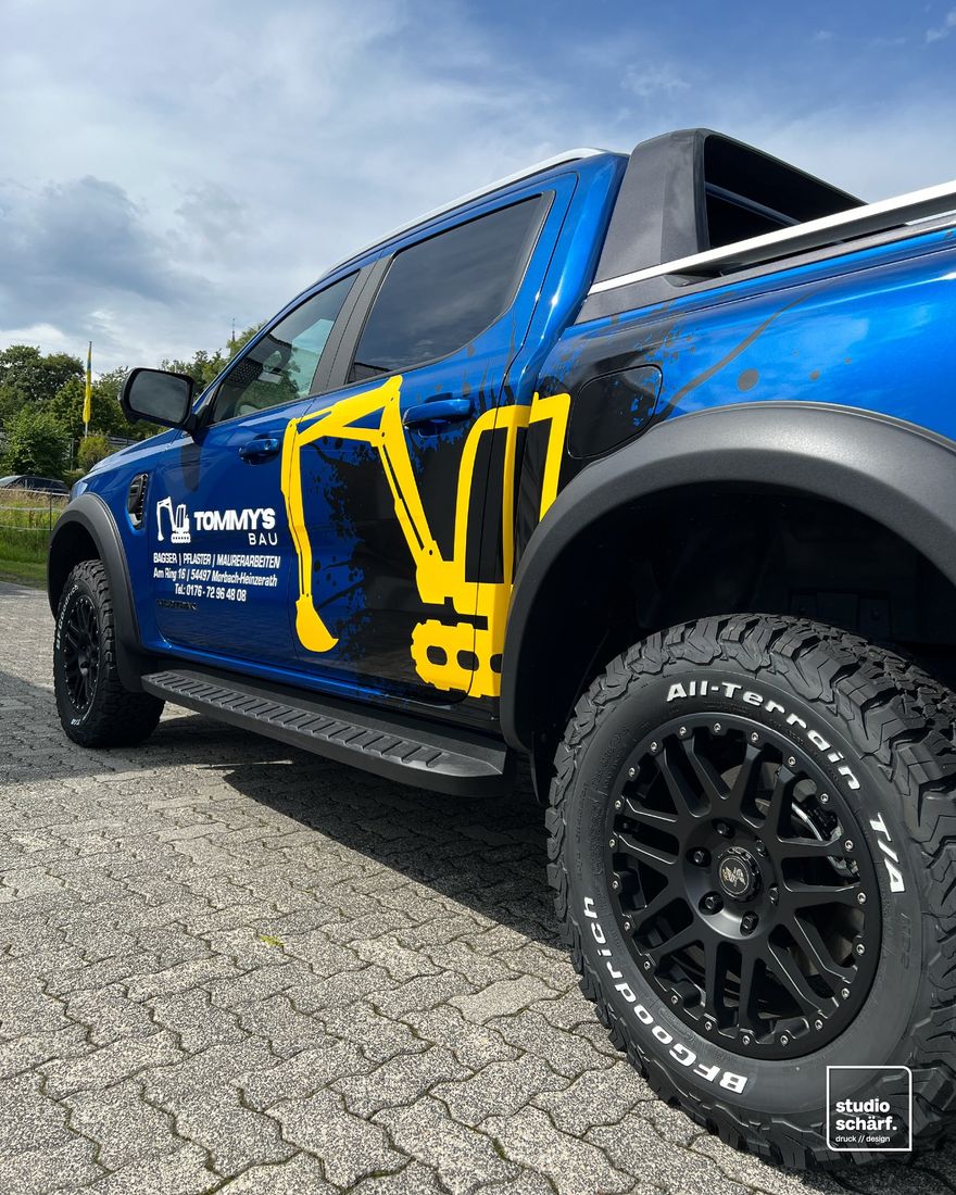 Teilfolierung mit Bagger-Motiv auf einem blauen Pick-up für Tommy's Bau